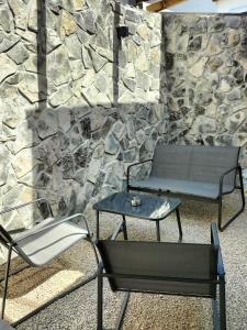 坎波马里诺Rambling Rooms的石墙前的长凳、桌子和椅子