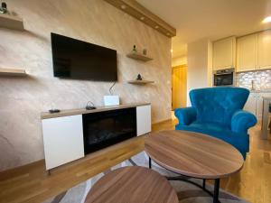 兹拉蒂博尔Nirvana 02的客厅配有电视、蓝椅和桌子