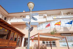 洛斯阿尔卡萨雷斯Destino De Sol De Los Alcazares的标志在有旗帜的建筑前的街道标志