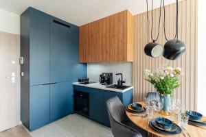 格但斯克Baltic Residence by LoftAffair的厨房配有蓝色橱柜和桌椅