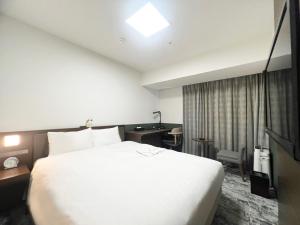 福山福山站前里士满酒店的酒店客房设有一张白色大床和一张书桌