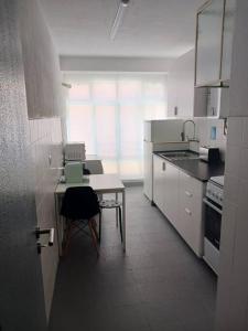 里斯本Simpático apartamento no centro的白色的厨房配有桌子和椅子