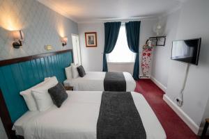 切尔滕纳姆Rising Sun Hotel by Greene King Inns的酒店客房设有两张床和电视。