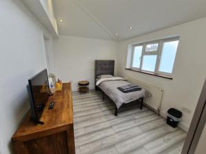 伦敦科尔尼Stylish Suites with kitchenette的一间卧室配有一张床、一张书桌和一台电视