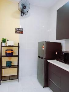 加影'Adn Homestay的厨房配有冰箱和墙上的风扇