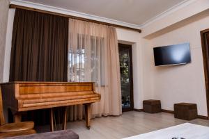 迪利然Maestro Rest House Dilijan的客厅配有钢琴和平面电视。