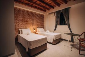 SaittasPine View Hotel (Okella)的一间卧室设有两张床和砖墙