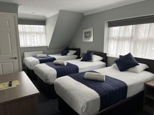 霍利Corner House Hotel Gatwick with Holiday Parking的蓝色和白色的客房内的三张床