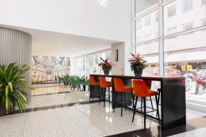 米兰IH Hotels Milano Centrale的大堂设有带橙色椅子的酒吧