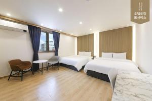 全州市Hotel Torang Jeonju的酒店客房带两张床和一张桌子以及椅子。