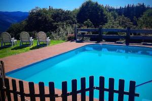 Murueta-Orozkocaserio vasco con piscina y barbacoa的一个带椅子和围栏的蓝色游泳池