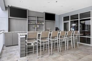 卡纳维拉尔角TownePlace Suites by Marriott Cape Canaveral Cocoa Beach的厨房配有带椅子的酒吧和一台电视