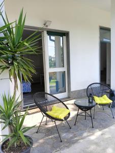 卡萨诺韦Sleep & Fly Malpensa的庭院里设有三把带黄色靠垫的椅子