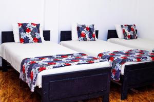 汉班托塔Hotel Sanasuma的配有红色和蓝色棉被的房间的三张床