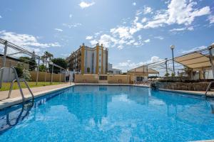 奇克拉纳－德拉弗龙特拉Hotel Balneario de Chiclana的一座大型游泳池,其建筑背景为: