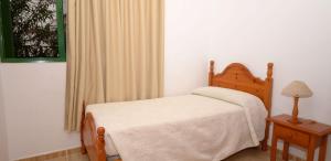 塔马达斯特Apartamento Bajo en el Tamaduste Zona Privilegiada的一间卧室配有一张床、一张桌子和一个窗户。