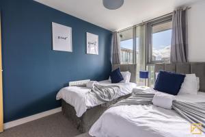 米尔顿凯恩斯Luxury 2-bed In central MK By Valore Property Services的蓝色墙壁客房的两张床