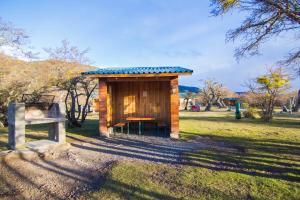 纳塔列斯港Glamping Río Serrano - Caja Los Andes的田野上的小木棚,带长凳