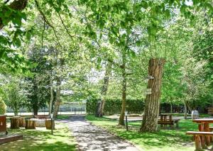 枫丹白露Demeures de Campagne Château de Fontainebleau的公园里长着长椅和桌子,树木