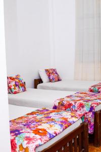 汉班托塔Hotel Sanasuma的客房配有两张带花卉枕头的床。