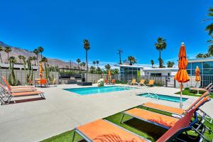 棕榈泉Stunning Palm Springs 2 Bedroom Condo的一个带草坪椅和遮阳伞的游泳池