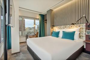 鹿特丹Motel One Rotterdam的卧室配有带蓝色枕头的大型白色床