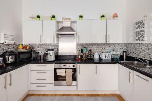伦敦Two double bedroom duplex flat的厨房配有白色橱柜和黑色台面