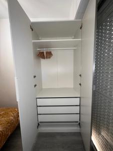 昂蒂布Charmant 2 Pièces的步入式衣柜,配有白色橱柜和一张床