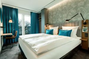 波恩Motel One Bonn-Hauptbahnhof的卧室配有一张蓝色色调的大型白色床。