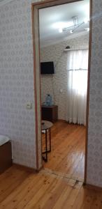 苏呼米Гостевой дом Анастасия的一间设有桌子和窗户的客房和一间铺有木地板的客房