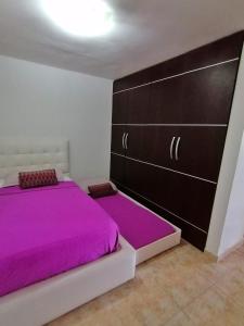 PampatarLo mejor de isla Margarita的一间卧室配有一张带紫色床单的大床