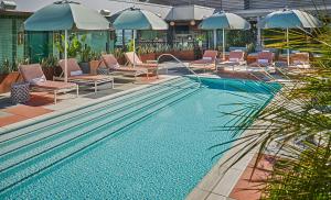 洛杉矶Pendry West Hollywood的一个带躺椅和遮阳伞的游泳池