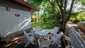 格但斯克Captain's Cottage 110m2, near Sopot, beaches, with a garden, grill & free parking的庭院配有白色的椅子、桌子和一棵树