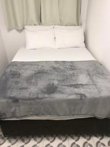 加拉尼温斯Pequena Pousada的一张位于小房间的床,配有灰色的毯子