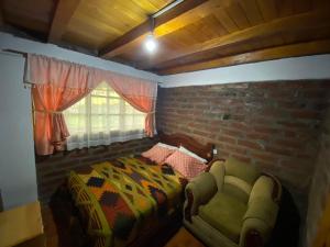 拉塔昆加Rumipaxi Lodge的一间卧室配有一张床、一把椅子和砖墙