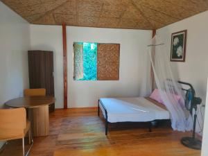 TocdocMarquis garden Eco-cottages的一间卧室配有一张床、一张桌子和一个窗户。