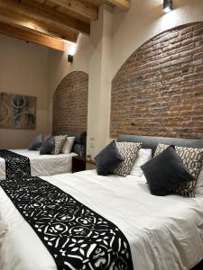 特科早特拉Hotel Del Valle的砖墙客房的两张床