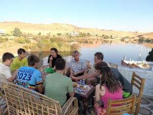阿斯旺Seko Kato Nile View Hostel的一群人坐在湖边的桌子旁