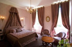 博讷夏兰奇城堡酒店的一间卧室配有一张床、两把椅子和一张桌子