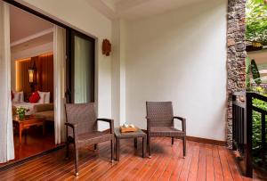景洪市西双版纳洲际度假酒店的一个带两把椅子和一张桌子的门廊和一间卧室