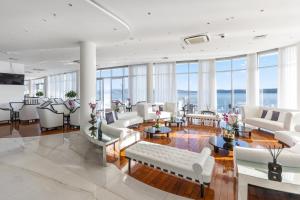 塞尔瑟Luxury Hotel Amabilis的大型客厅配有白色家具和窗户。