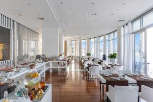 塞尔瑟Luxury Hotel Amabilis的餐厅设有桌子和白色的椅子以及窗户。