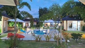 Ban ChamrungPool Villa, Resort, Mae Ramphueng Beach, Ban Phe, Rayong, Residence M Thailand的后院设有游泳池,配有椅子和树木