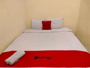日惹RedDoorz near Kampus UNY Jogja的红色和白色的床,上面有红色枕头