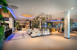 科隆Leonardo Royal Hotel Cologne Bonn Airport的沙龙设有白色的椅子和植物