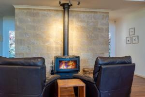 亚林加普Kangaroo Lodge - Yallingup的客厅配有2把皮椅和炉灶