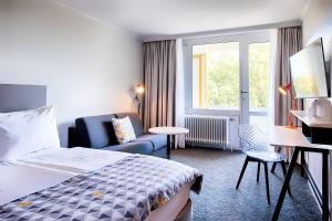 慕尼黑Holiday Inn Munich - South, an IHG Hotel的酒店的客房 - 带一张床、椅子和窗户