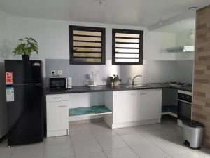 圣勒Maison de vacances Leu ti coin des ô的厨房配有白色橱柜和黑色冰箱。