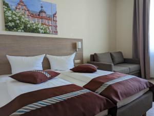 美因茨美因茨酒店的一间卧室配有带枕头的床铺和沙发