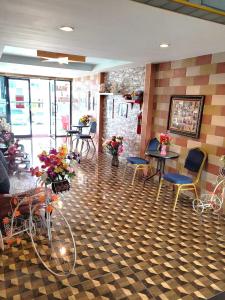 Ban Kut Ngongกานต์สินี อินน์ รีสอร์ท的一间设有桌椅和鲜花的等候室